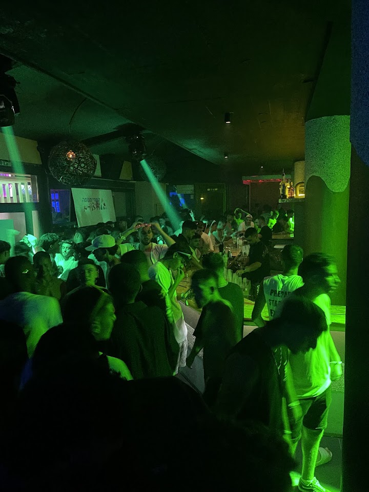 A packed dance floor under green lights at Kudo